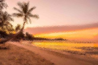 Sunset over a sandy beach with palm trees on the left and a golden sky reflecting on the water.
