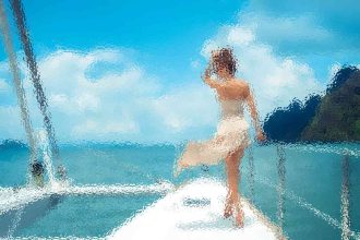 Woman in a white dress stepping onto a white boat deck near clear turquoise water and blue sky.