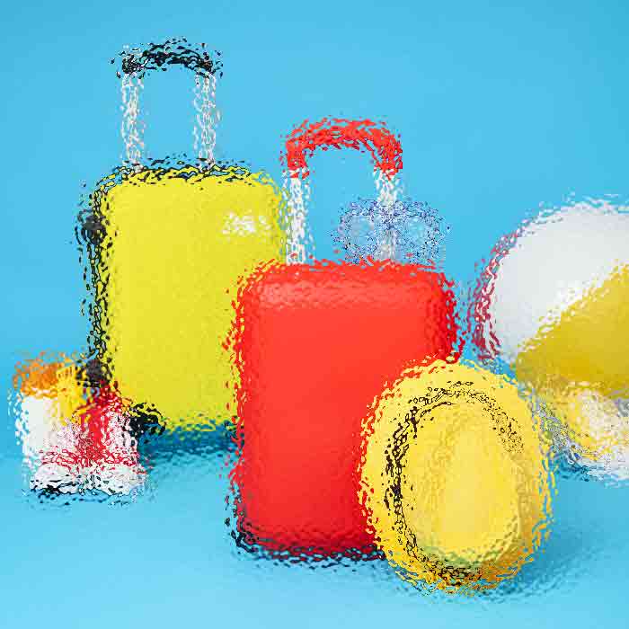 Brightly colored travel luggage set on a blue background: yellow suitcase, red bag with a handle, and a yellow oval object nearby, all with a glossy abstract look.