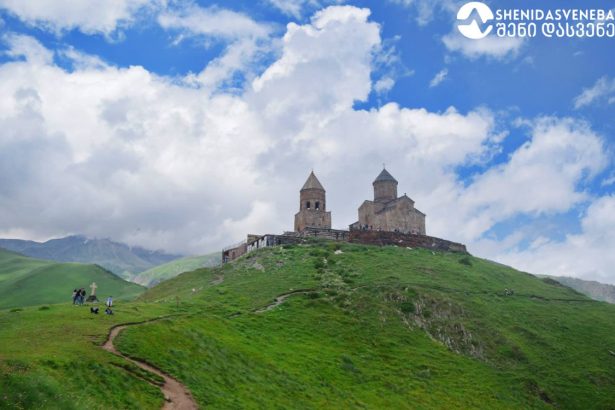 გერგეტის სამების ტაძარი მაღალ მთაზე ღრუბლებს შორის კაზბეგის ფონზე