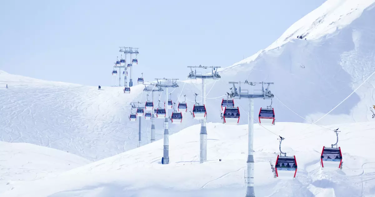 Chairlift over a snow-covered mountain with red gondolas and blue sky.