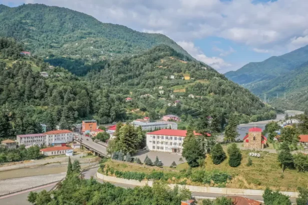A small mountain village with colorful rooftops nestled among green hills and a winding road.