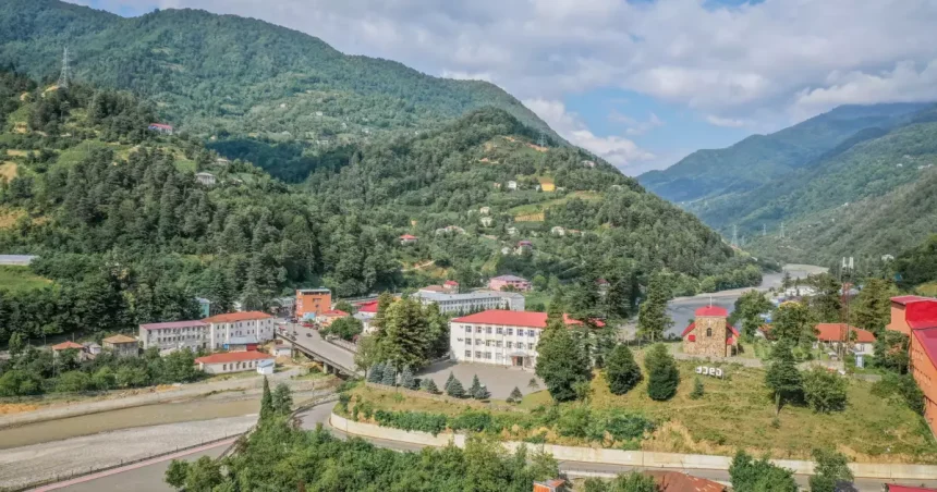 A small mountain village with colorful rooftops nestled among green hills and a winding road.