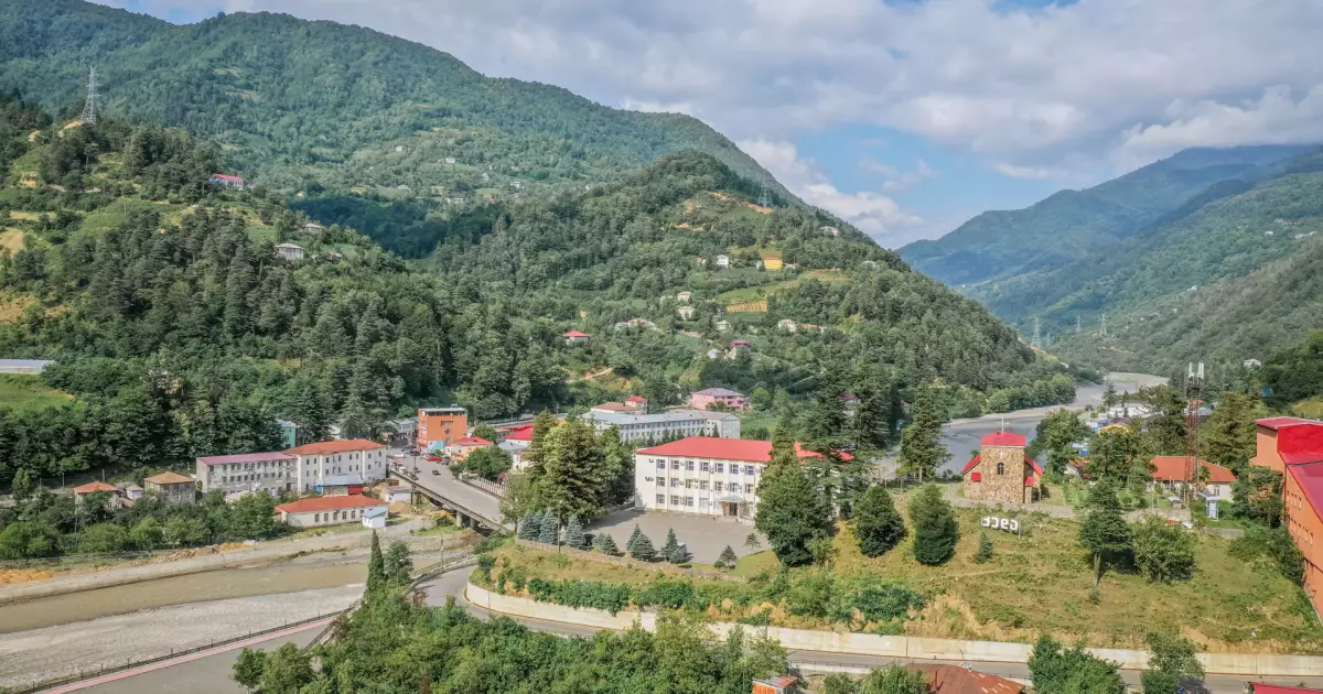 A small mountain village with colorful rooftops nestled among green hills and a winding road.