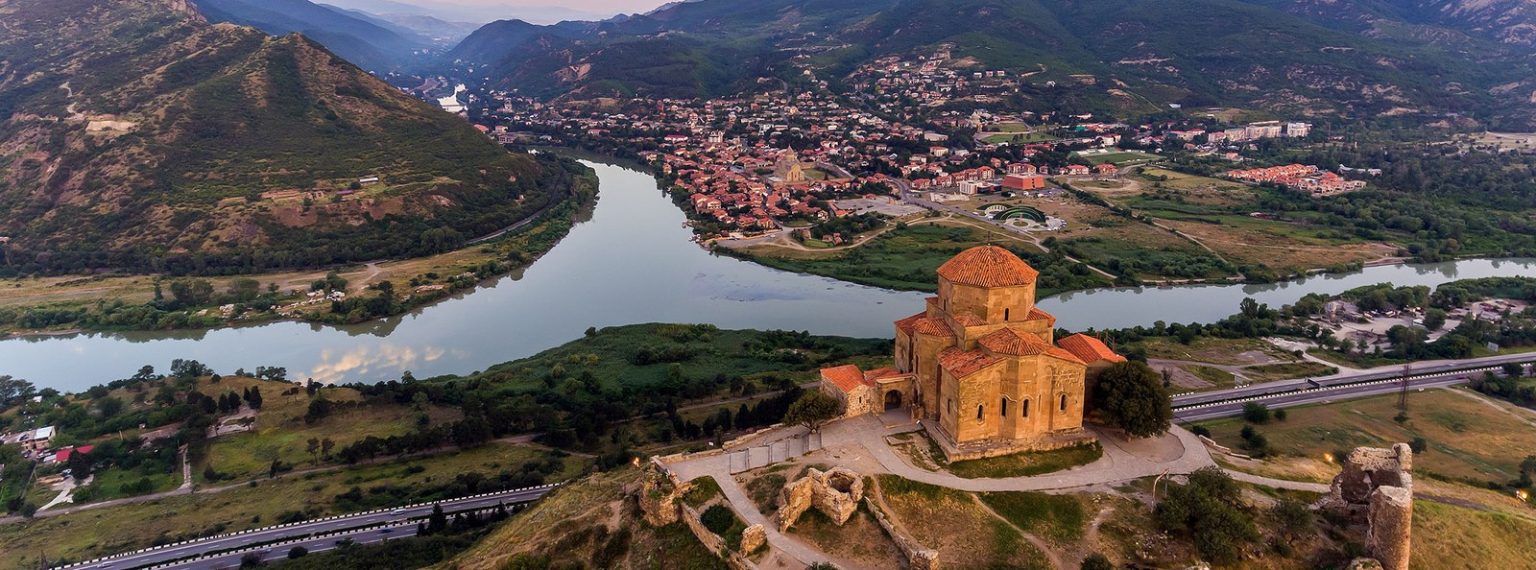 Ancient stone church on a hill overlooking a winding river and a town tucked in a valley.