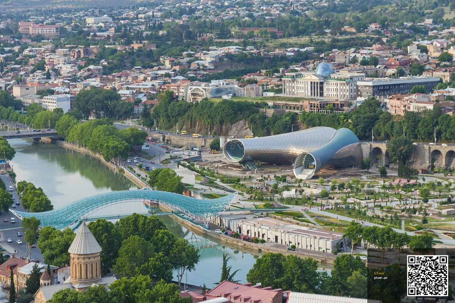 Aerial view of central Tbilisi showing the river, Peace Bridge and modern concert hall.