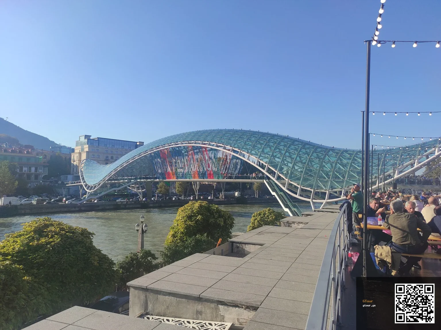 Crowds gather at Tbilisi's Bridge of Peace during a city festival, a key sight for visitors.