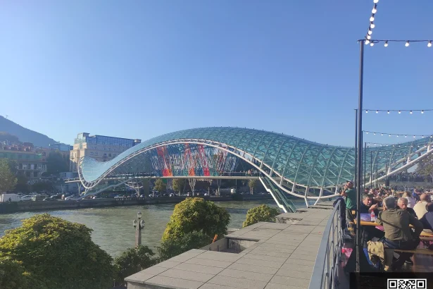 Crowds gather at Tbilisi's Bridge of Peace during a city festival, a key sight for visitors.