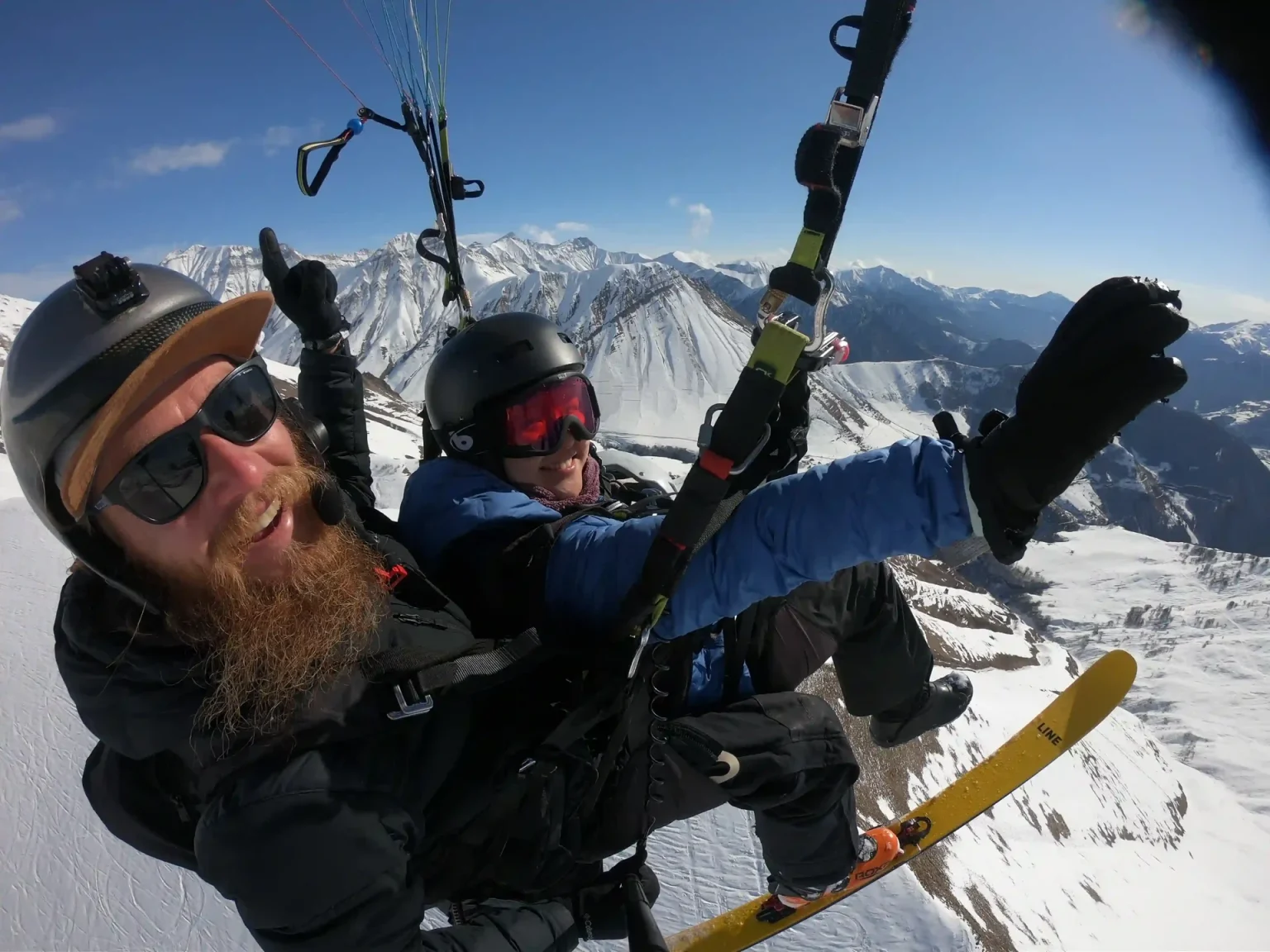 Tandem paragliders soar over the snowy peaks above Gudauri ski resort.