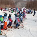 Children lined up on skis during a beginners' lesson at a ski resort, Georgia-style group class.