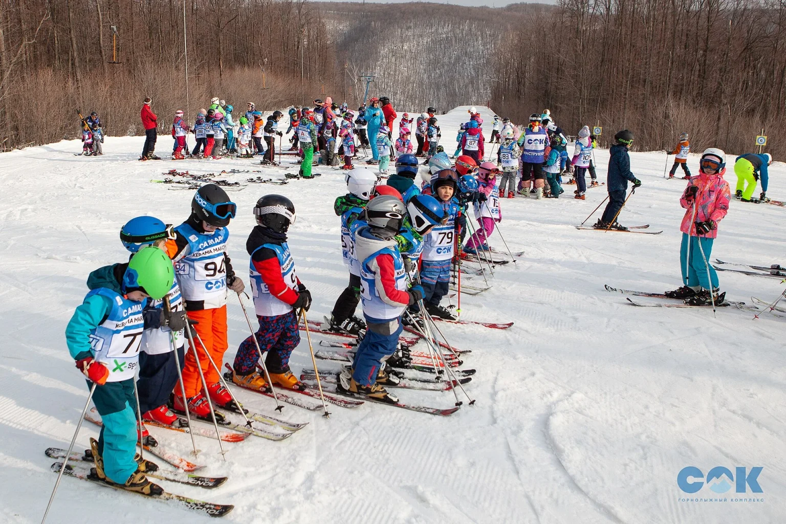 Children lined up on skis during a beginners' lesson at a ski resort, Georgia-style group class.