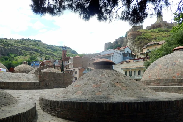 Brick domes of Tbilisi's historic sulphur baths rise beneath the Narikala fortress in Abanotubani.