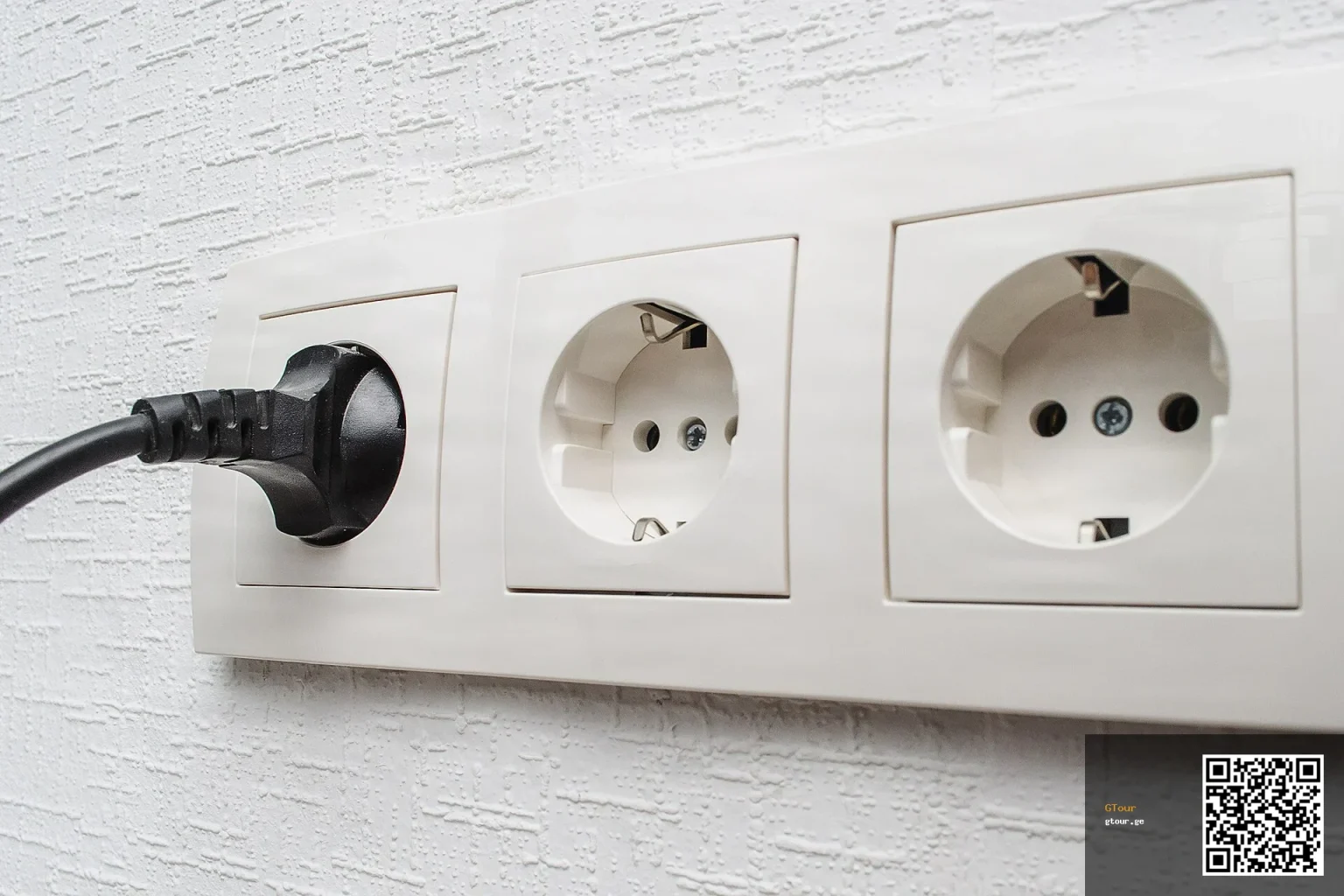 A European Type F/Schuko-style socket with a plug inserted, similar to Georgia's Type C/F outlets.