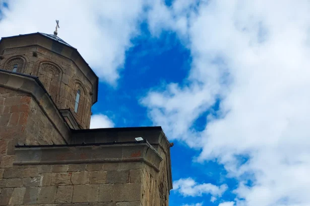 Visitors walk along the stone terrace at Gergeti Trinity Church high above Kazbegi.