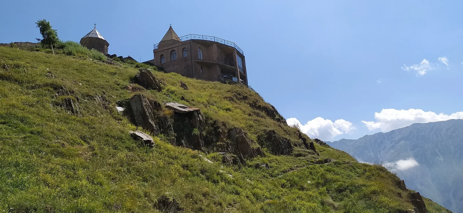 Gergeti Trinity Church perched on its hilltop above Kazbegi, a must-see mountain stop.