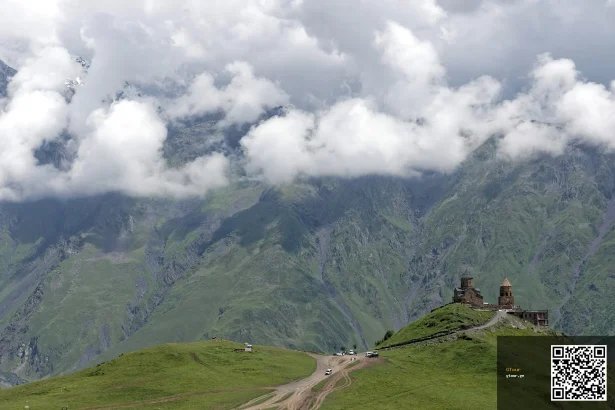Gergeti Trinity Church on its hilltop with 4x4 track and cars climbing up from Kazbegi.