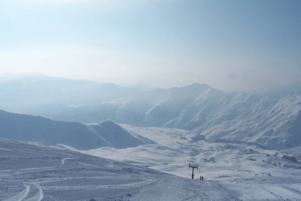 A chairlift and skiers crossing the vast snowy slopes above Gudauri resort.
