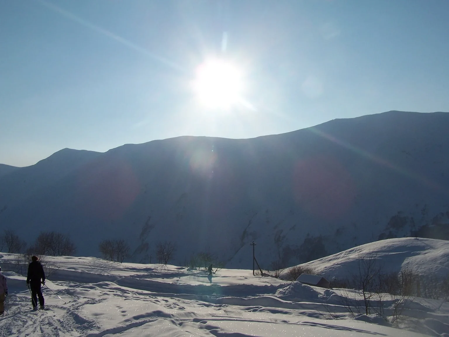A skier crosses a sunlit snowfield beneath the mountains above Gudauri.