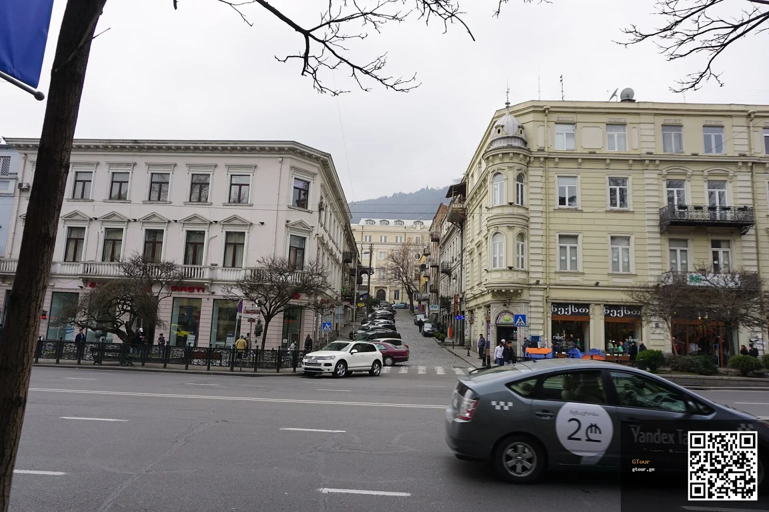 A green Yandex Taxi car drives through central Tbilisi near Laghidze Street.