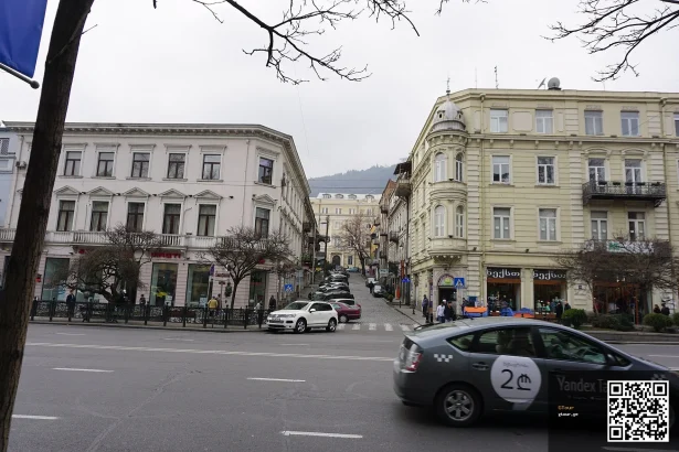 A green Yandex Taxi car drives through central Tbilisi near Laghidze Street.