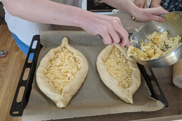 Adjarian khachapuri being filled with cheese, a classic Georgian dish for visitors to try.