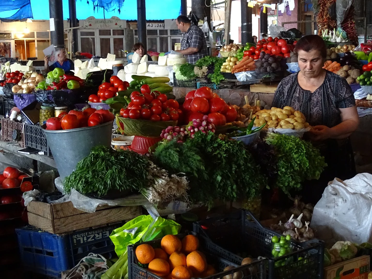 A Telavi market vendor arranges fresh vegetables, cheese and herbs for sale.
