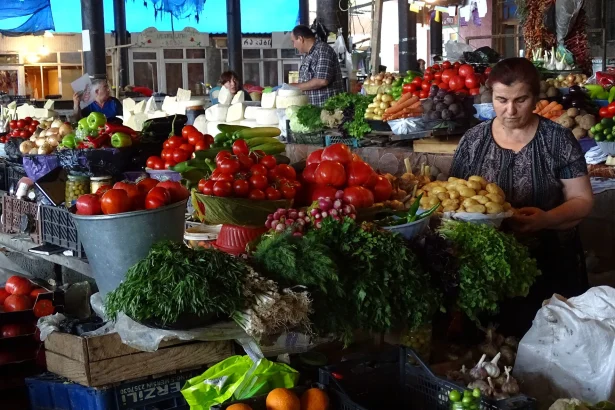 A Telavi market vendor arranges fresh vegetables, cheese and herbs for sale.