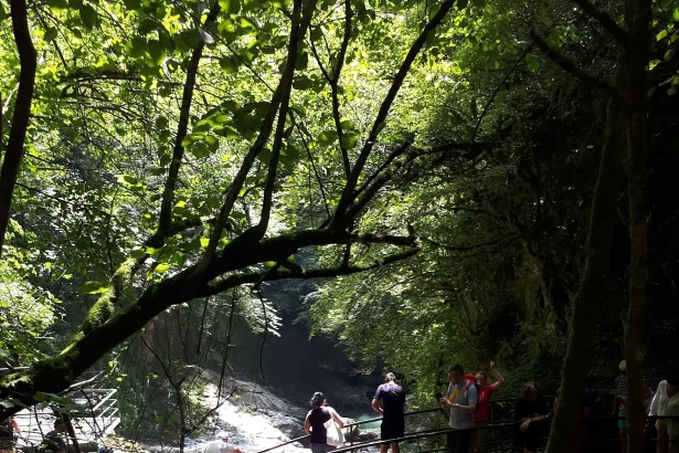 Tourists cross a bridge over the turquoise water of Martvili Canyon, a popular Georgian day trip.