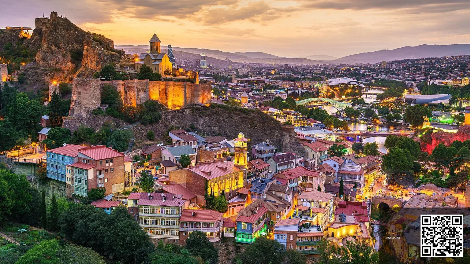 Narikala Fortress overlooks Tbilisi's old town and Abanotubani district at dusk.
