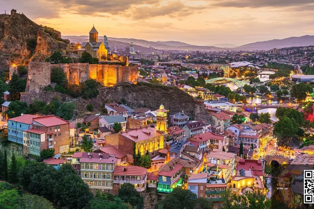 Narikala Fortress overlooks Tbilisi's old town and Abanotubani district at dusk.