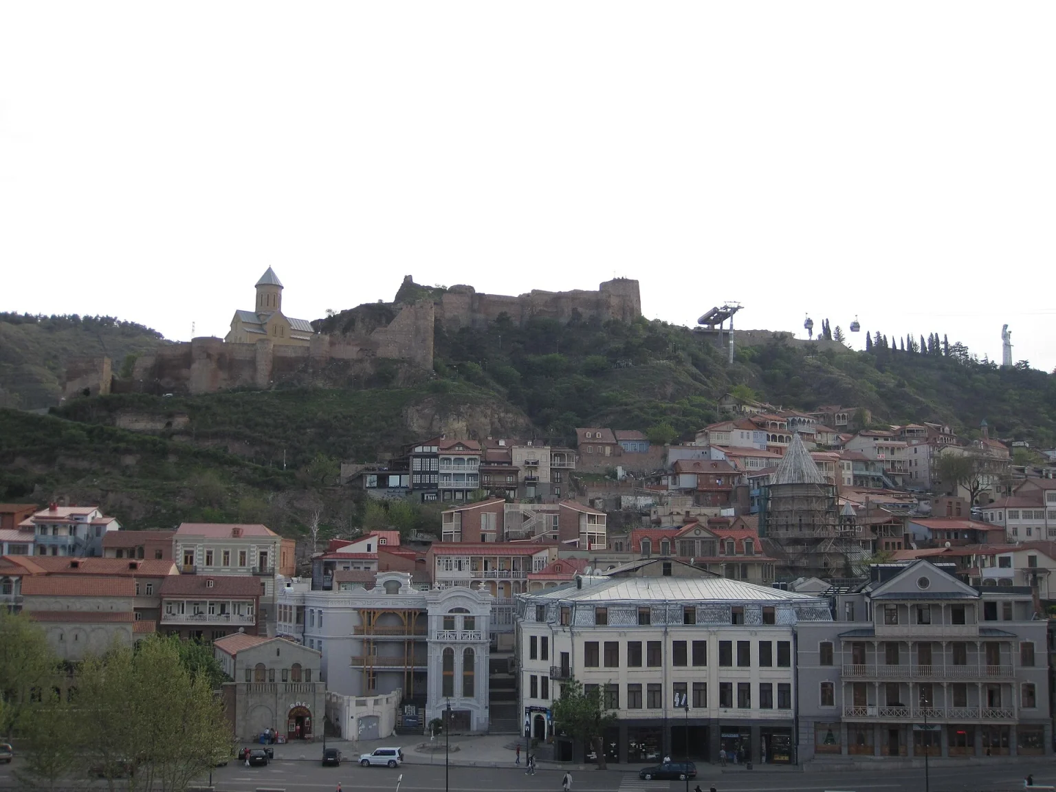 Old Tbilisi's historic quarter and Narikala fortress hillside, green with early spring foliage.