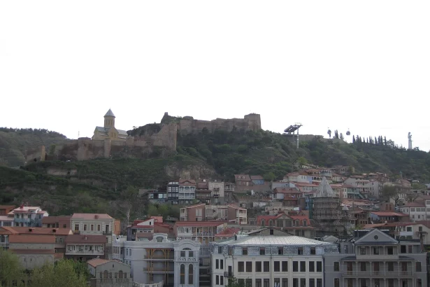 Old Tbilisi's historic quarter and Narikala fortress hillside, green with early spring foliage.