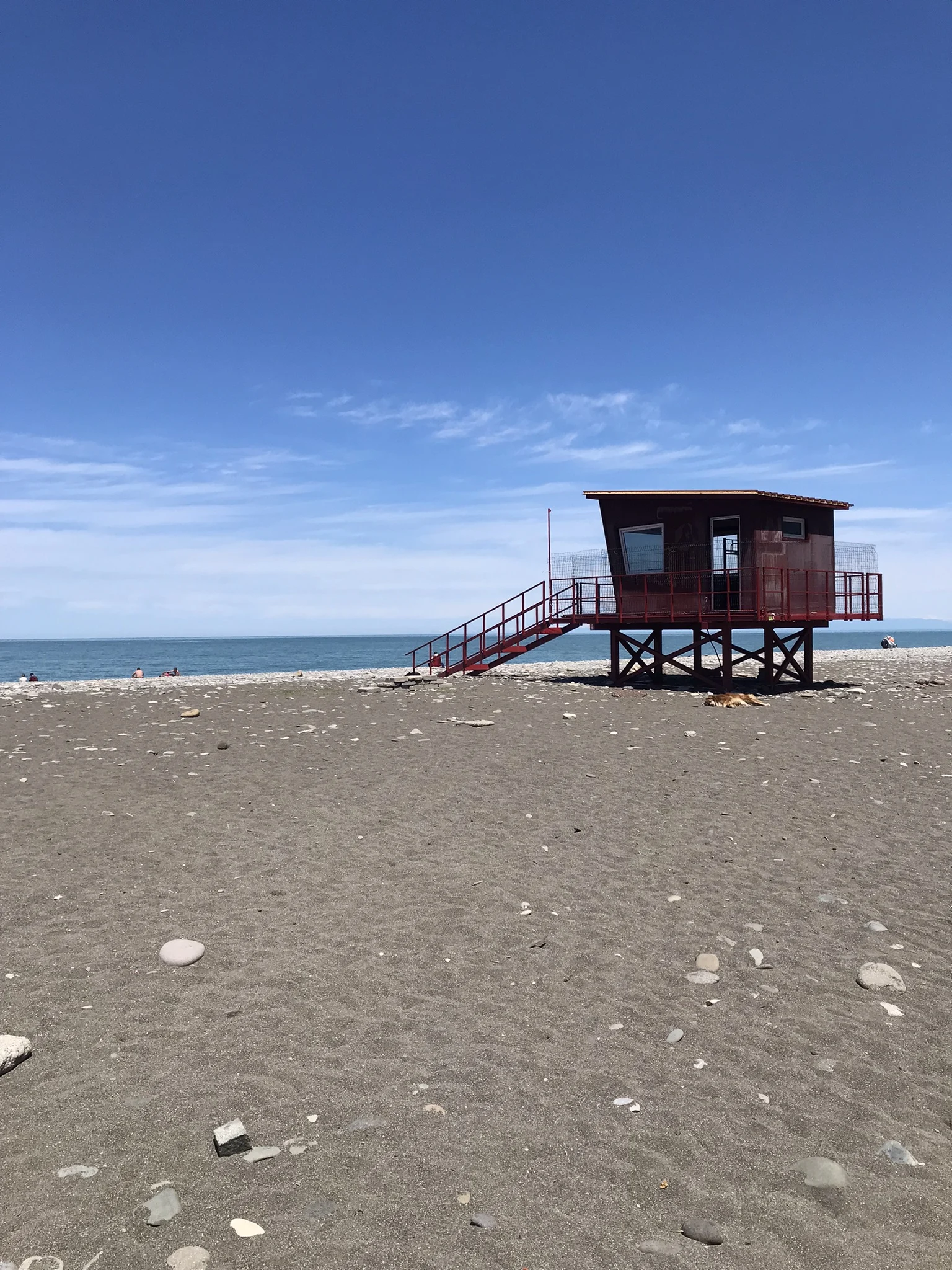 A red lifeguard tower stands on Batumi's pebble beach by the Black Sea.