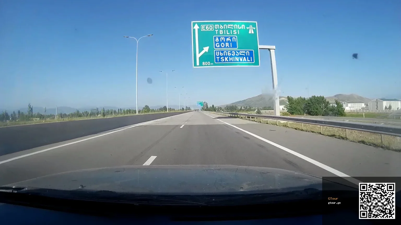 Highway sign near Tbilisi shows the E60 route and exits, typical of Georgia's road signage drivers must navigate.