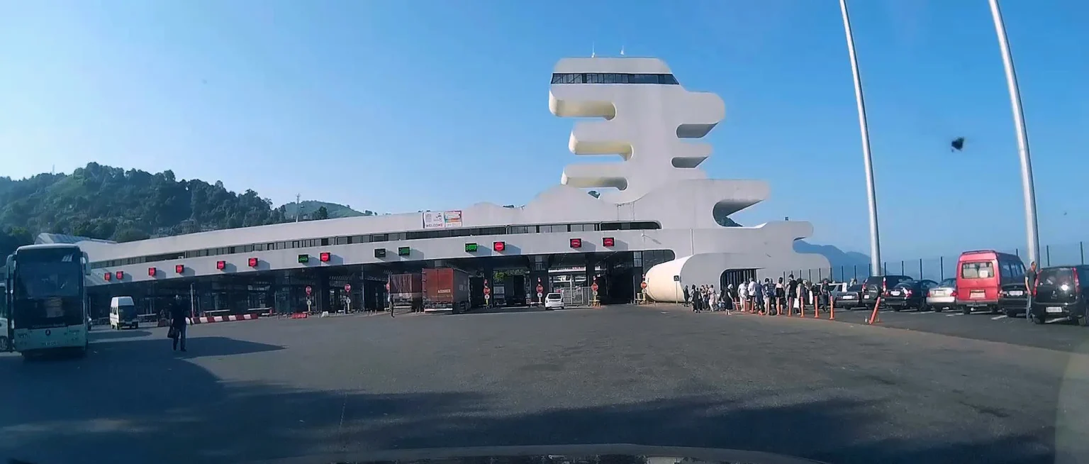 Vehicles and travelers queue at the futuristic Sarpi checkpoint on the Georgia-Turkey border.